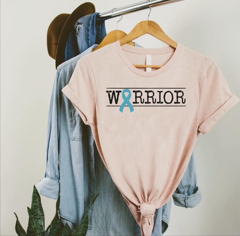 a pink shirt with a blue ribbon on the front and a blue ribbon on the