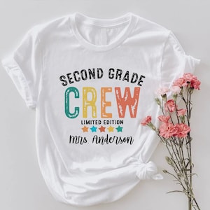 a white t - shirt with the words, second grade crew printed on it