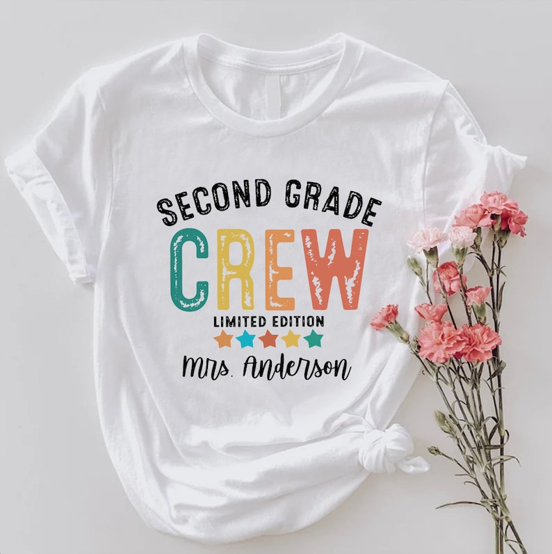 a white t - shirt with the words, second grade crew printed on it