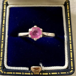 Peut inclure: Une bague en argent avec une pierre précieuse rose dans un écrin à bijoux en velours bleu.