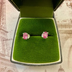 Peut inclure: Une paire de boucles d'oreilles en argent avec des pierres précieuses ovales roses serties à griffes. Les boucles d'oreilles sont présentées dans un écrin à bijoux en velours vert.