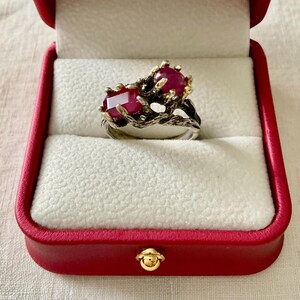 Peut inclure: Une bague en argent avec un motif de branche sertie de deux rubis. La bague est dans un écrin à bague en velours rouge.