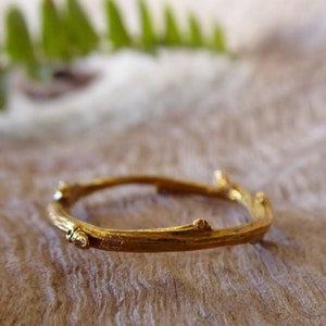 Può includere: Un anello d'oro a forma di ramo con piccole protuberanze sulla superficie.