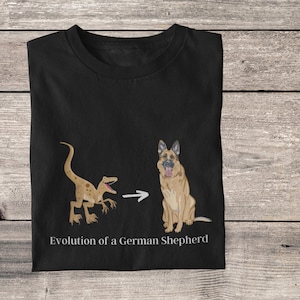 May include: Black t-shirt with a white graphic of a dinosaur evolving into a German Shepherd dog. The text "Evolution of a German Shepherd" is printed below the graphic.