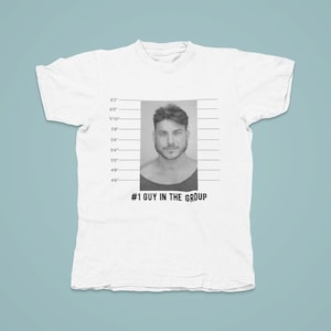 May include: White t-shirt with a black and white mugshot image of a man with the text '#1 GUY IN THE GROUP' printed below the image.
