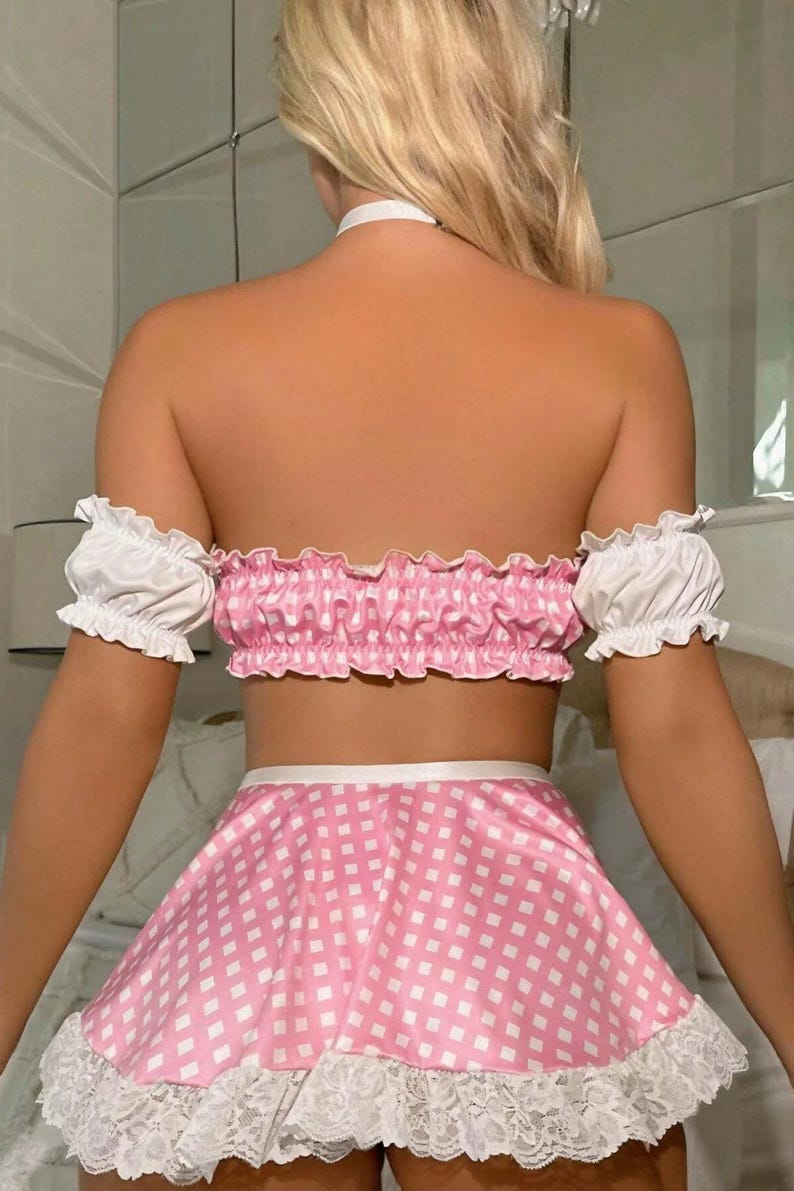 Pode incluir: Conjunto de duas pe&ccedil;as rosa e branco com estampa xadrez vichy. O top &eacute; sem al&ccedil;as com mangas franzidas. A saia &eacute; uma minissaia com acabamento em renda branca. Um colar gargantilha branco tamb&eacute;m &eacute; vis&iacute;vel.