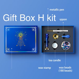 May include: A blue gift box with a gold sun design and the text "Gift Box H kit". The box contains a wax stamp, a metal spoon, a tea candle, and a jar of wax beads.