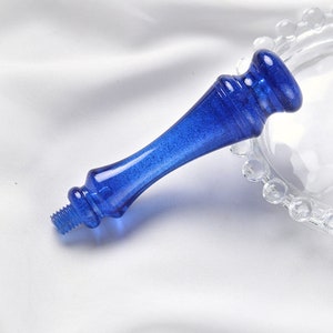 Puede incluir: Un mango de sello de cera de vidrio azul con un extremo roscado. El mango tiene un acabado brillante.