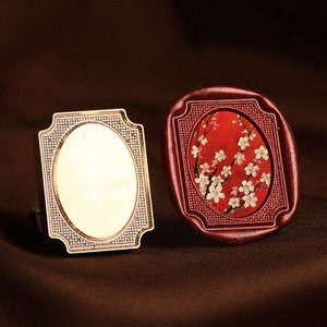 May include: Two ornate frames, one with a white oval and the other with a red background and a white floral design.