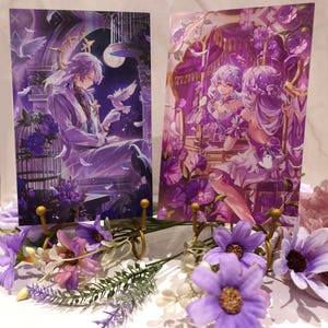 May include: Two purple and white anime character illustrations printed on cardstock and displayed on gold metal stands. The illustrations are surrounded by purple and white flowers.