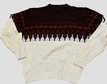 May include: A brown and white knitted sweater with a geometric pattern. The sweater has a crew neck and long sleeves.