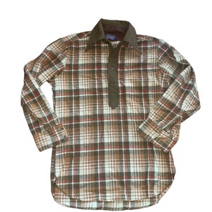 May include: A long-sleeved plaid shirt with a brown, white, and red plaid pattern. The shirt has a button-up collar and a single button closure at the neck. The shirt is made of a soft, comfortable fabric.