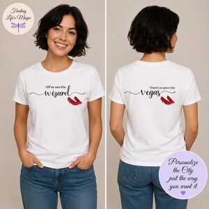 May include: A white short-sleeved t-shirt featuring black cursive text and red high-heeled shoes. The front displays the text Off to see the wizard, while the back displays the text There's no place like Vegas, both accompanied by red shoe graphics.
