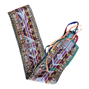 May include: A colorful woven belt with a geometric pattern in shades of red, blue, yellow, and green. The belt has multiple straps in various colors. The design is intricate and detailed, showcasing a traditional textile style.