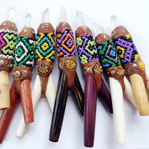 May include: Eight colourful beaded wands with clear crystal tips and wooden handles. The wands are decorated with geometric patterns and leather accents.