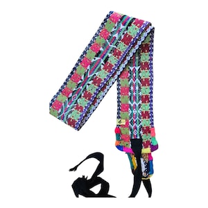 May include: A colorful woven belt with a geometric pattern in pink, green, red, and purple. The belt has a black tie closure and a small tag with the number 6. The belt is likely used for fashion or as an accessory.