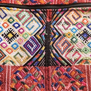 Op de afbeelding: Een kleurrijke geweven stoffen tas met een ritssluiting. De stof heeft een geometrisch patroon in tinten rood, blauw, groen, geel en zwart.