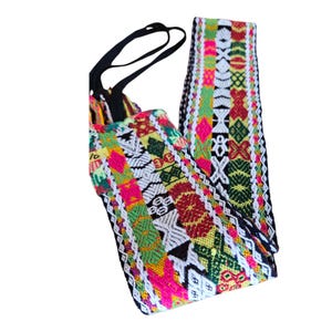 May include: A colorful, woven headband with a black elastic band. The headband features a vibrant pattern of pink, green, yellow, and red geometric designs on a white background. The woven fabric is approximately 1 inch wide.