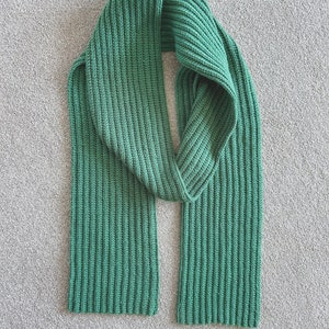 May include: A green knitted scarf with a ribbed texture.