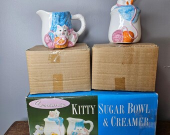 Juego de azucarero y cremera de cerámica con diseño de gatito de PMC, blanco y azul, estilo kitsch con ovillo de lana y caja.