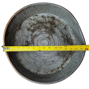 Può includere: Una bacinella rotonda in metallo grigio usurato con un motivo a cerchi concentrici testurizzati sulla superficie interna. Un metro a nastro giallo Stanley è teso al centro, indicando un diametro di circa 40,6 centimetri per la bacinella.