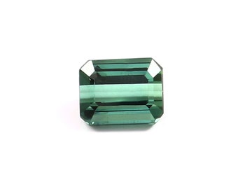 May include: A green emerald cut gemstone with a rectangular shape.