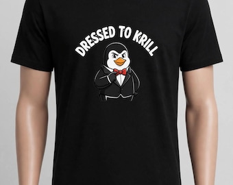 May include: A black short-sleeved t-shirt featuring a graphic of a penguin wearing a black tuxedo with a red bow tie. Above the penguin, the text reads DRESSED TO KRILL in white capital letters. The design is centered on the chest of the shirt.