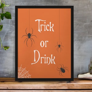 K&ouml;nnte beinhalten: Ein gerahmtes orangefarbenes Poster mit dem Text "Trick or Drink" in Wei&szlig;. Es befinden sich drei schwarze Spinnen-Silhouetten, die von der Oberseite des Posters h&auml;ngen. In der linken unteren Ecke befindet sich ein Spinnennetz.