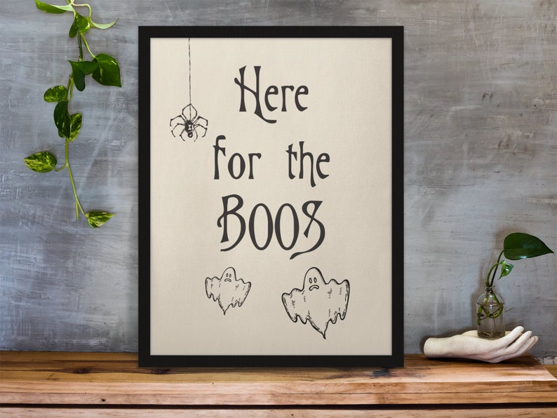 K&ouml;nnte beinhalten: Ein schwarzer gerahmter Druck mit wei&szlig;em Hintergrund. Der Druck sagt "Here for the Booos" mit einer Spinne und zwei Geistern, die darauf gezeichnet sind.