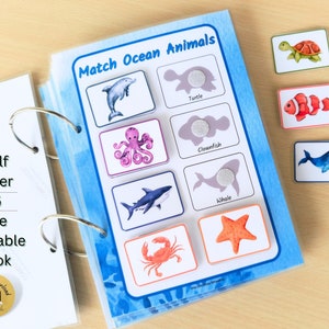 May include: A printable book with a blue background and images of ocean animals. The book has a title that says "Match Ocean Animals". The book includes images of a dolphin, turtle, octopus, clownfish, whale, crab, and starfish. There are also separate cards with images of the animals.
