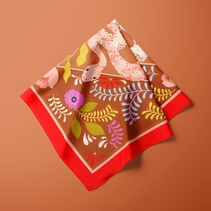 May include: A square scarf with a brown background and a red border. The scarf features a floral and snake design in pink, yellow, and purple. The scarf is folded in a diamond shape.