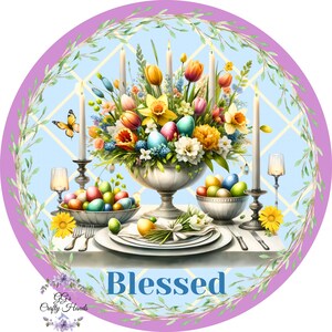 May include: A round, purple and blue, decorative plate with a white background. The plate features a floral arrangement with candles, a butterfly, and a table setting with eggs. The text "Blessed" is written in blue letters on the plate.