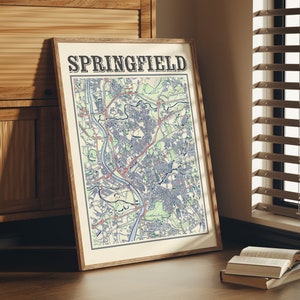 Puede incluir: Un mapa enmarcado de Springfield con el nombre de la ciudad en una fuente de estilo vintage. El mapa está impreso en azul, rojo y verde sobre un fondo blanco.