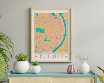 May include: A framed print of a vintage-style map of St. Louis, Missouri. The map is in shades of yellow, orange, pink, and green, with a blue river winding through the city. The text "ST. LOUIS" is printed in orange at the bottom of the map.