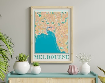 Puede incluir: Una impresión enmarcada de un mapa de Melbourne, Australia. El mapa es de estilo vintage con una combinación de colores amarillo y naranja. La ciudad está delineada en azul y el agua circundante es de color turquesa. El texto "MELBOURNE" está impreso en verde en la parte inferior de la impresión.