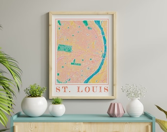 May include: A framed print of a colorful map of St. Louis, Missouri. The map is in shades of yellow, orange, pink, and green. The city's name is printed in orange at the bottom of the print.