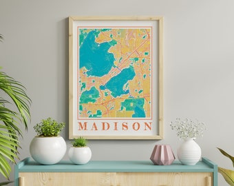 May include: A framed print of a map of Madison, Wisconsin. The map is in a vintage style with a yellow, orange, and green color scheme. The city's name is printed in white at the bottom of the map.