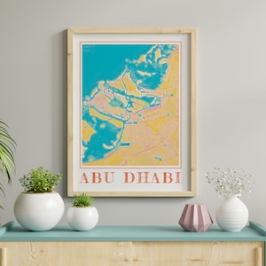 May include: A framed print of a map of Abu Dhabi with a yellow and blue colour scheme. The map is surrounded by a wooden frame and the city name is printed in orange at the bottom of the print.