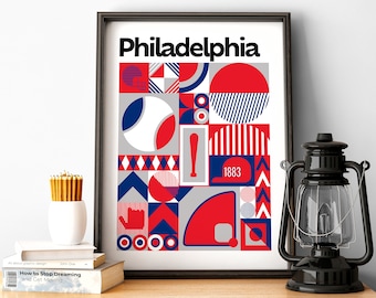 May include: A framed print with a geometric design in red, white, and blue. The print features the word "Philadelphia" and the year "1883".