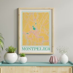 Könnte beinhalten: Ein gerahmter Karten-Druck von Montpellier, Frankreich, im minimalistischen Stil. Die Karte hat einen gelben Hintergrund mit türkisfarbenen und rosa Akzenten und einen türkisfarbenen Rahmen. Das Wort "MONTPELLIER" ist unten in Türkis gedruckt.