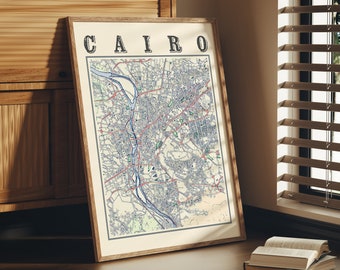 May include: A framed map of Cairo, Egypt, with the city name printed in bold letters at the top. The map is in a light brown wooden frame and is leaning against a wooden cabinet.
