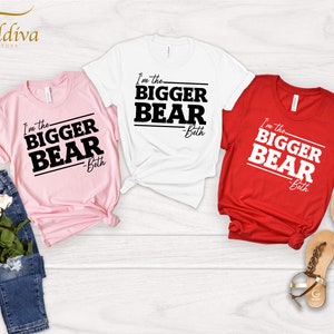 May include: Three t-shirts with the text "I'm the BIGGER BEAR - Beth" printed on them. The shirts are pink, white, and red.