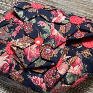May include: A dark blue fabric purse with a floral pattern and red buttons. The purse is made of fabric and has a quilted design.
