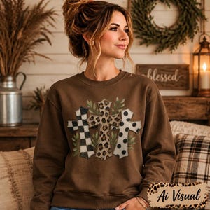 Digital sublimation instant download of A brown long-sleeve crewneck sweatshirt featuring a graphic print of three crosses. The left cross has a black and white checkered pattern, the center cross has a brown leopard print, and the right cross has a white and black polka dot pattern. PNG file transfer.