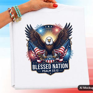 Könnte beinhalten: Ein weißes T-Shirt mit einer Grafik eines Weißkopfseeadlers mit ausgebreiteten Flügeln, platziert über zwei amerikanischen Flaggen und buntem Feuerwerk. Unter dem Adler befindet sich ein Schild mit dem Text BLESSED NATION und PSALM 33:12.
