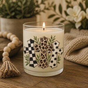 Digital sublimation instant download of A clear glass candle jar filled with white wax and a lit wick. The exterior features three cross illustrations: one with a black and white checkered pattern, one with a brown leopard print, and one with black polka dots, all accented by green leaves. PNG file transfer.