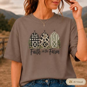 Może przedstawiać: Brązowy t-shirt z kr&oacute;tkim rękawem z grafiką przedstawiającą trzy stodoły w r&oacute;żnych wzorach: czarno-białą kratę, czarno-białe łaty krowie oraz zielono-białe paski. Pod stodołami znajduje się napis Faith on the Farm wykonany czarną czcionką.