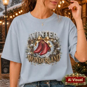 Puede incluir: Una camiseta azul claro con un gr&aacute;fico de dos patines de hielo rojos centrados en una corona de pi&ntilde;as y adornos plateados. El texto "WINTER WONDERLAND" est&aacute; impreso en una fuente dorada met&aacute;lica sobre y debajo de los patines.