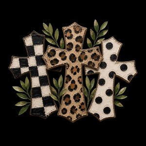 Pu&ograve; includere: Una decorazione da parete composta da tre ornamenti a forma di croce disposti insieme. La croce a sinistra presenta un motivo a scacchi bianco e nero, quella centrale una stampa leopardata beige e marrone, e quella a destra &egrave; bianca con pois neri.