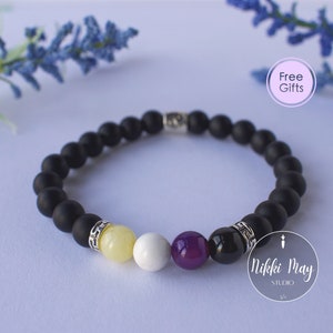 May include: A black beaded bracelet with yellow, white, purple, and black beads. The bracelet has silver accents and is on a white background.